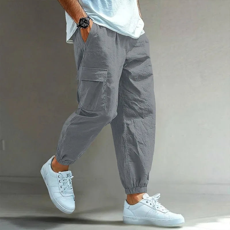 Grey cargo trousers with side pocket and elastic cuffs, close side view showing the soft crinkled cotton texture