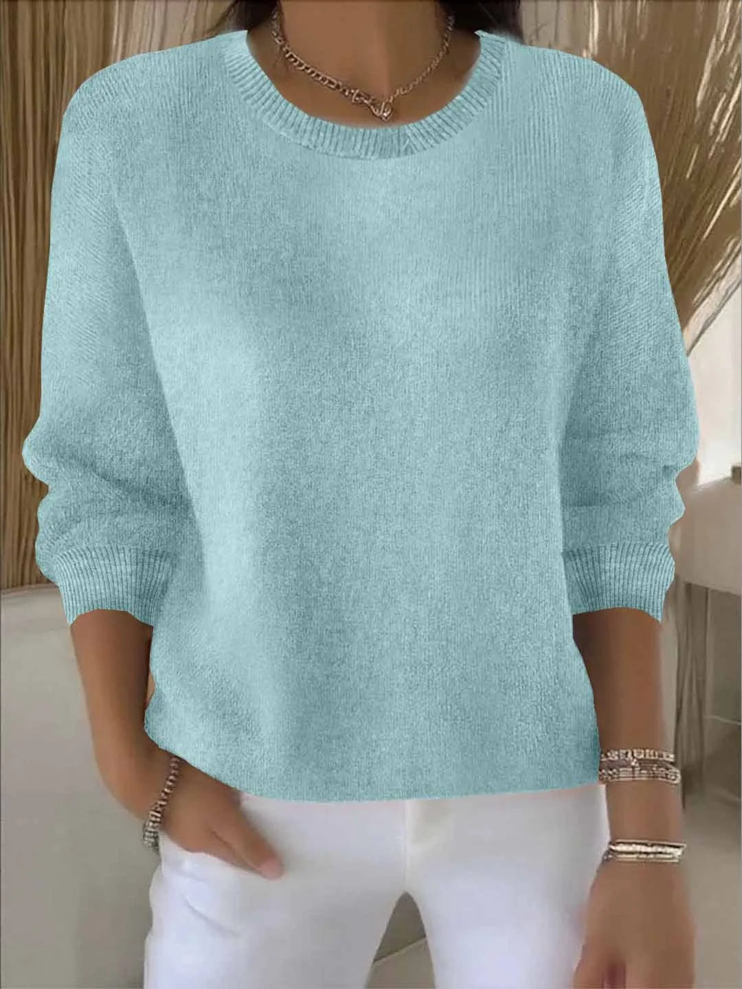 Close detail of ribbed round neckline and knit texture on a jumper worn with a chain necklace