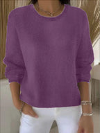 Front view of relaxed knit jumper with ribbed cuffs, worn with white trousers and bracelets