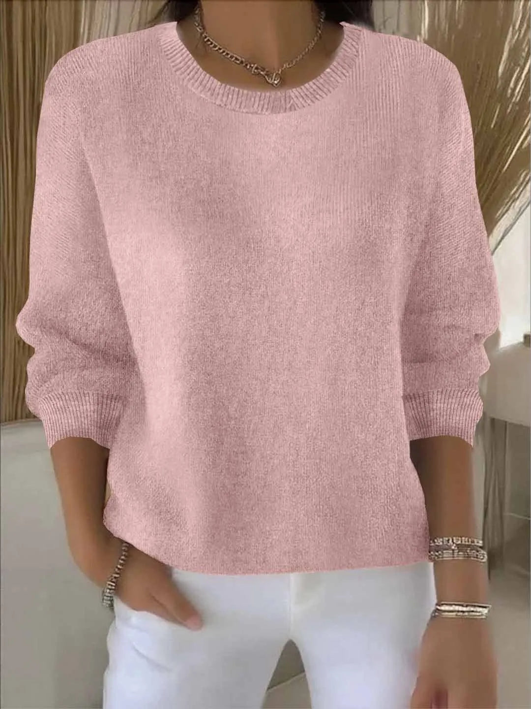 Soft pink knit jumper worn close-up showing ribbed crew neckline and relaxed knit texture