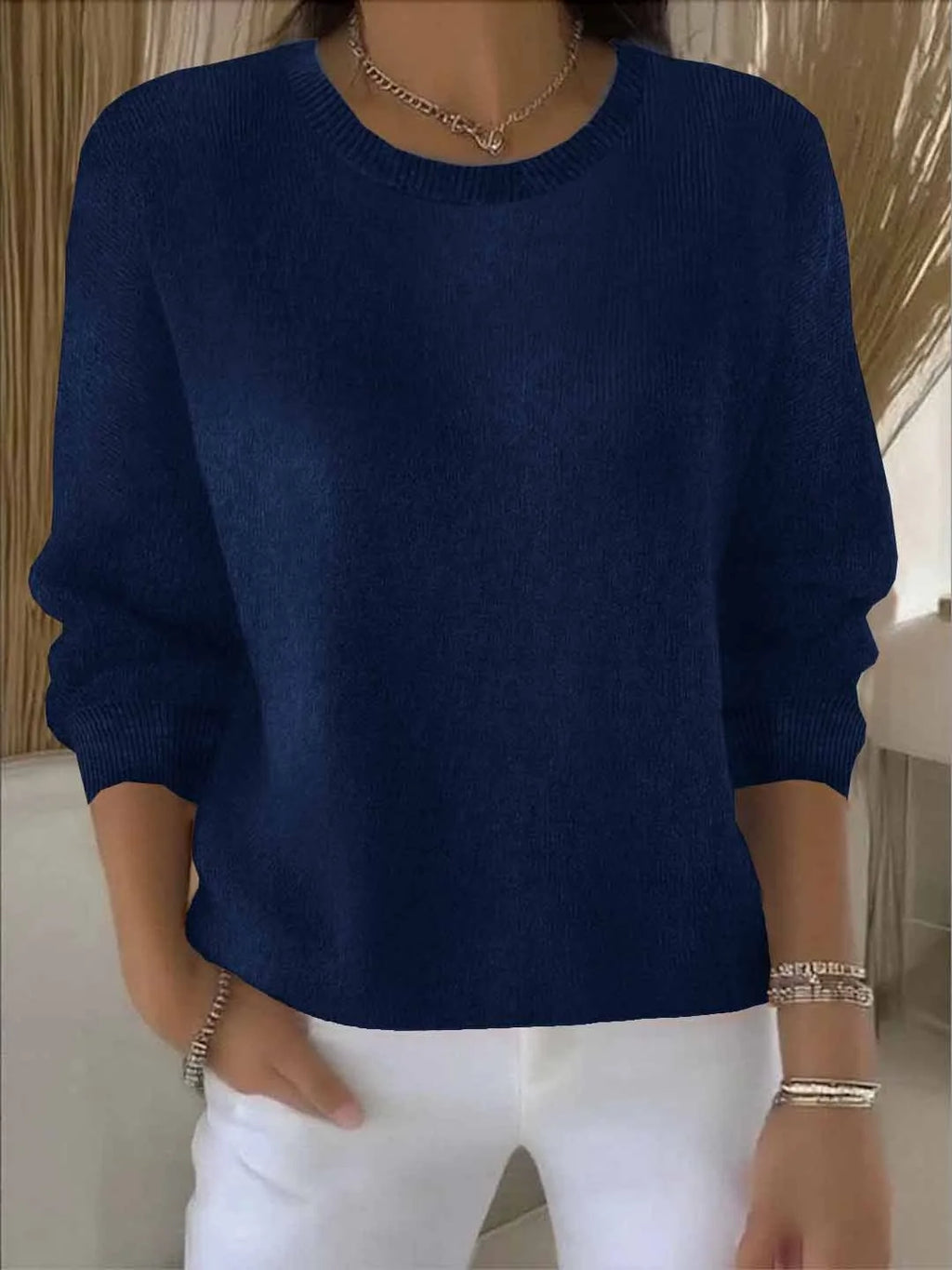 Navy blue knit jumper shown close-up with round ribbed neckline and relaxed long sleeves