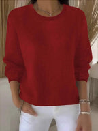 Bright red knit jumper close-up view showing ribbed crew neck and soft knit fabric