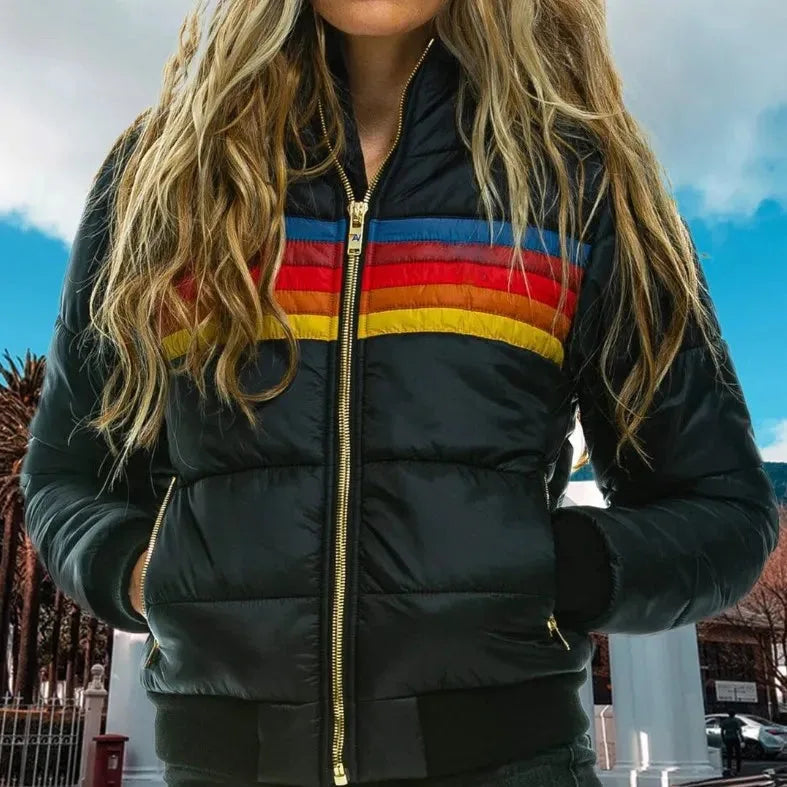 Close-up of black puffer jacket worn outdoors showing the striped chest panel and gold zip pockets