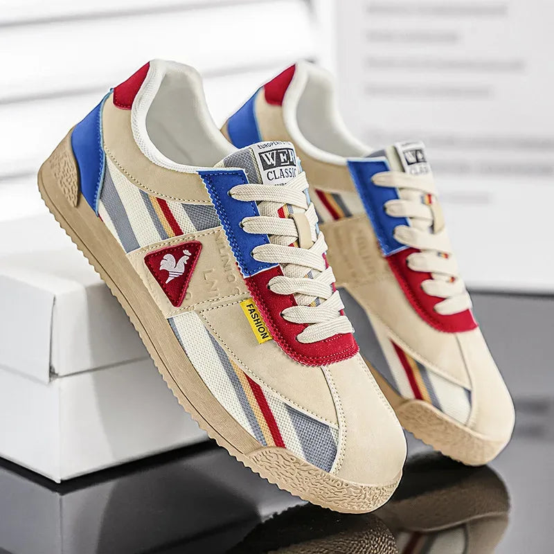 Three-quarter view of cream trainer with green and orange suede panels on a white box
