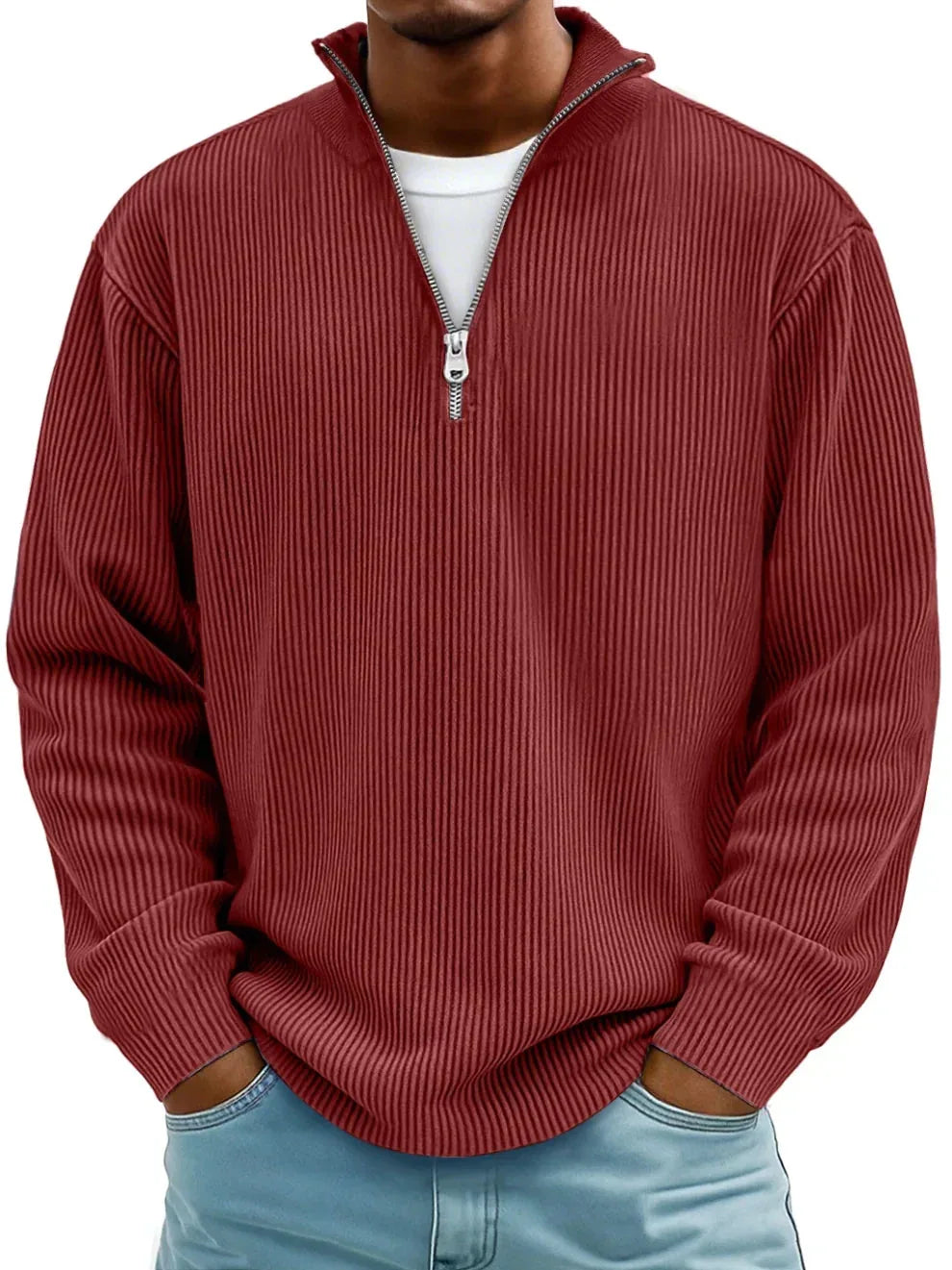 Man wearing a rust red ribbed quarter-zip jumper with silver zip, layered over a white t-shirt and light denim jeans