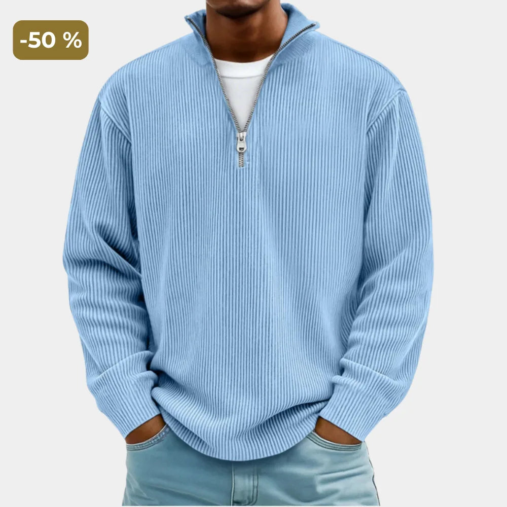 Man wearing a light blue ribbed quarter-zip jumper with silver zip, hands in pockets, front close-up view