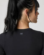 Close-up of the back neckline showing the woven brand label and ribbed texture of the black crop top