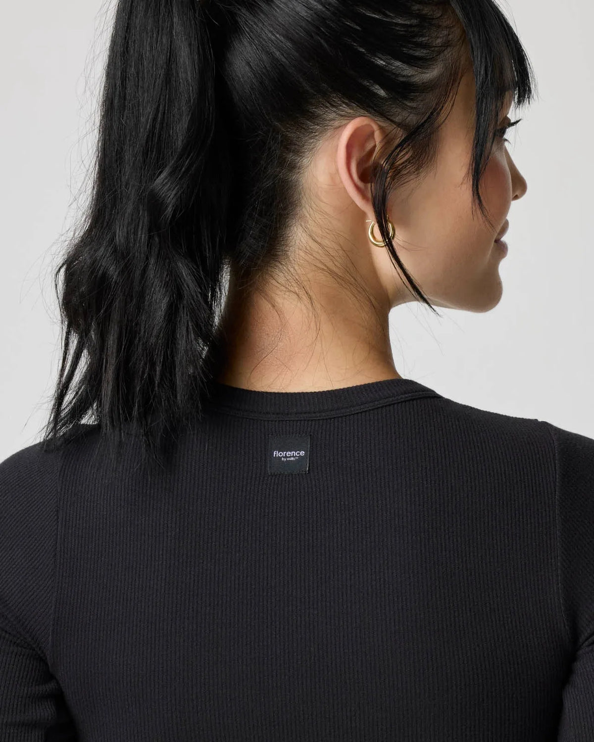 Close-up of the back neckline showing the woven brand label and ribbed texture of the black crop top