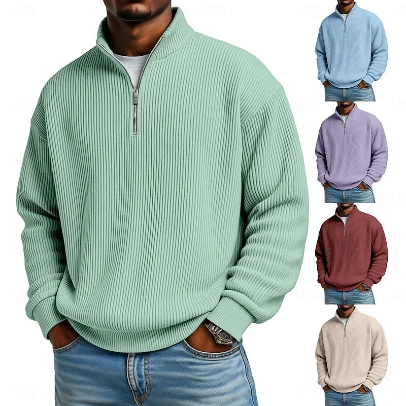 Man wearing an oversized ribbed quarter-zip pullover in sage green, paired with a white t-shirt and blue jeans