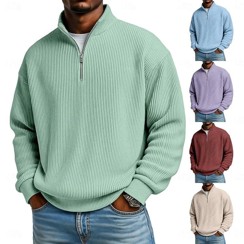 Man wearing an oversized ribbed quarter-zip pullover in sage green, paired with a white t-shirt and blue jeans