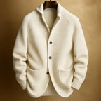 Cream white ribbed knit cardigan with notch collar and dark buttons, hanging against a soft tan background