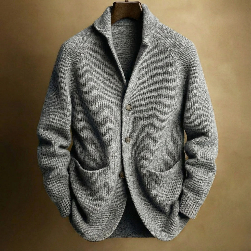 Grey ribbed knit cardigan with notch collar and front patch pockets, hanging against a warm backdrop