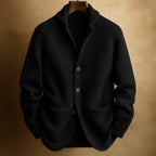 Black ribbed knit cardigan with notch collar and patch pockets, displayed on a wooden hanger