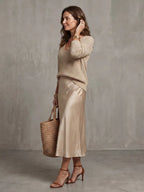 Front view showing the V-neckline depth of the knit jumper layered with delicate gold jewellery