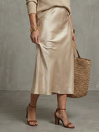 Woman holding the woven straw tote bag while wearing the pink knit jumper and satin skirt
