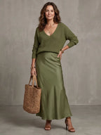 Walking shot from behind showing the satin skirt swaying at the midi length hem