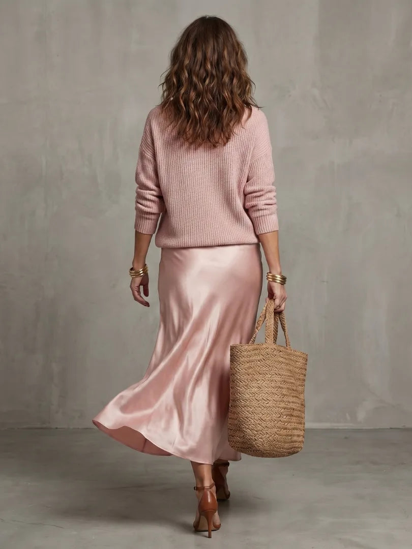 Back view showing the relaxed drop shoulder of the pink jumper and the flowing fall of the satin bias skirt
