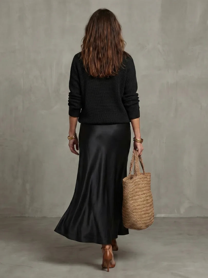 Back view of the black knit jumper and satin bias skirt, showing the clean drape and midi length