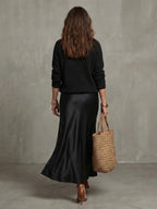 Back view of the black knit jumper and satin bias skirt, showing the clean drape and midi length