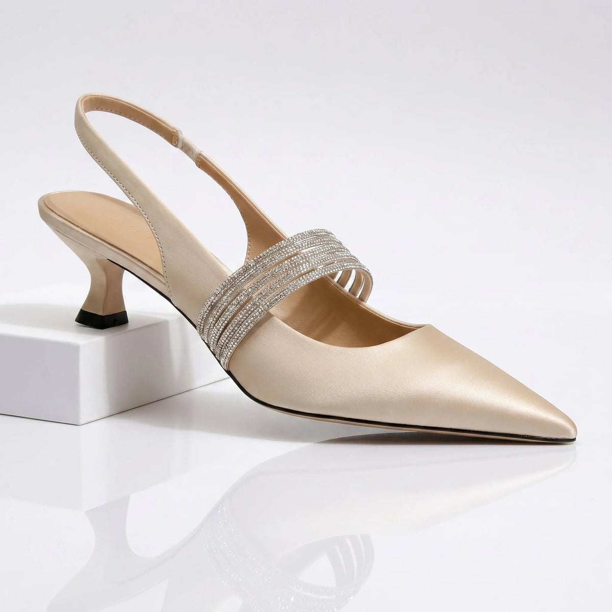 Side view of champagne satin kitten heel pumps with crystal slingback strap on white pedestal