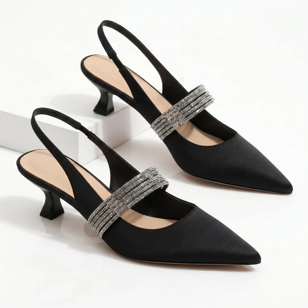 Side view of black satin kitten heel slingbacks with crystal strap detail on white pedestal