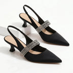 Side view of black satin kitten heel slingbacks with crystal strap detail on white pedestal