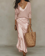 Model wearing the satin slip dress in soft pink under a matching pink knit jumper, layered look