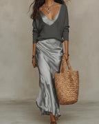 Model wearing the satin slip dress in grey under a charcoal grey ribbed jumper, front view