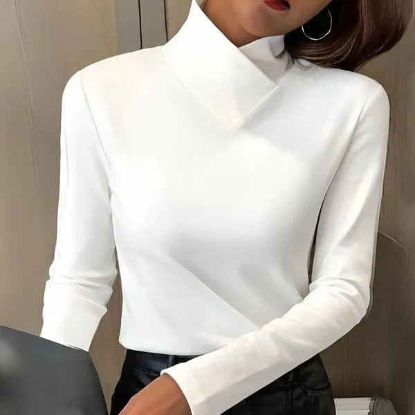 Close-up of a white asymmetric collar polo neck jumper with long sleeves, worn with black trousers.