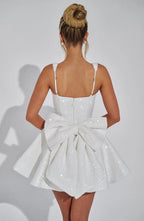 Back view showing the ivory sequin mini dress with a large oversized bow detail covering the open back