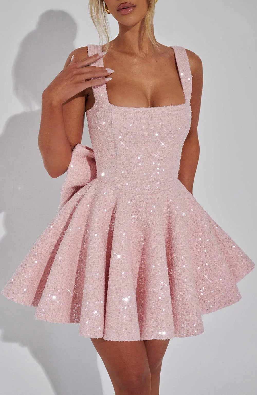 Side view of the blush pink sequin mini dress with square neckline, wide straps and side bow detail