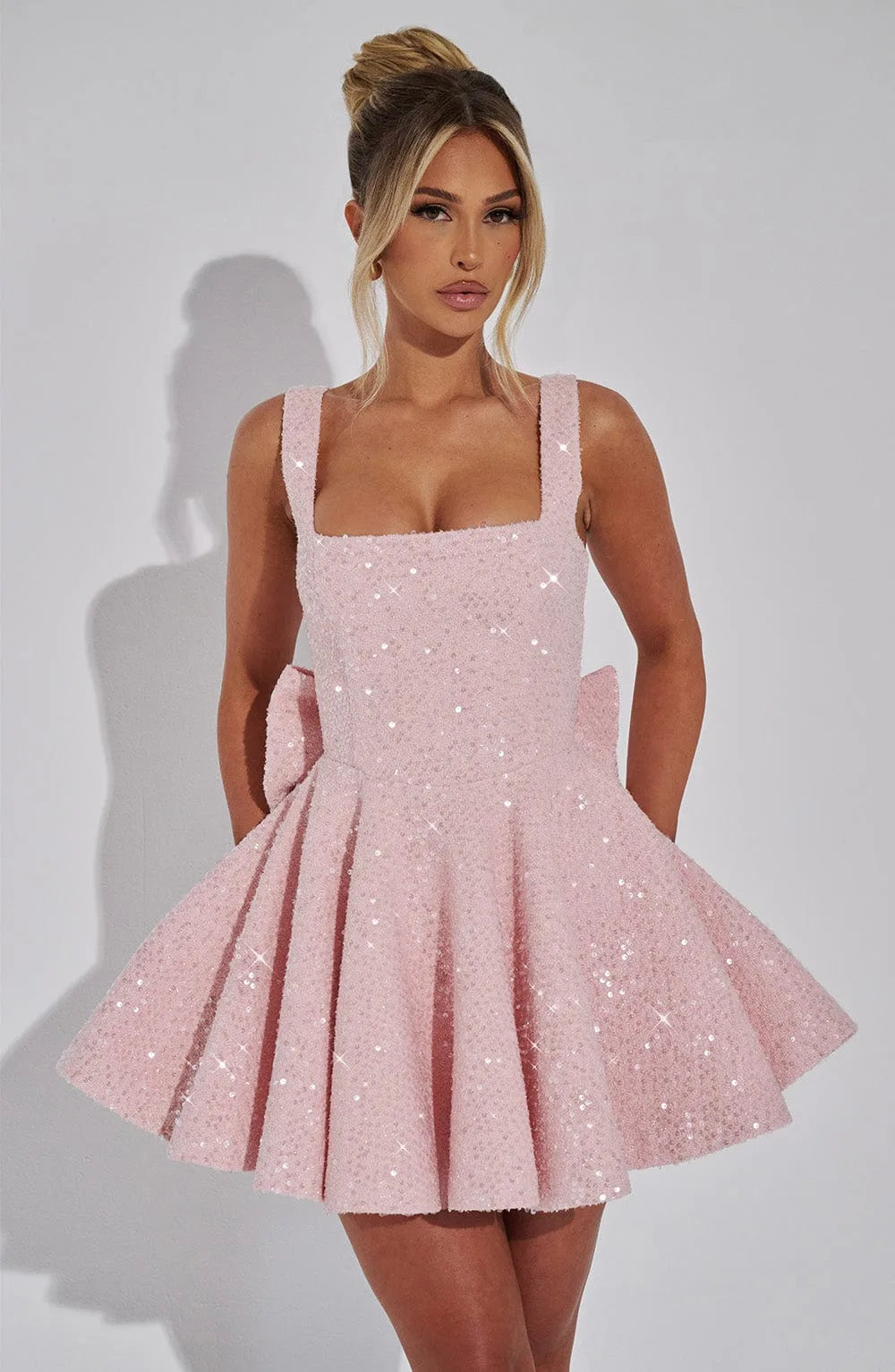 Front view close-up of the blush pink sequinned bodice and skirt with a woman's hand resting near the neckline
