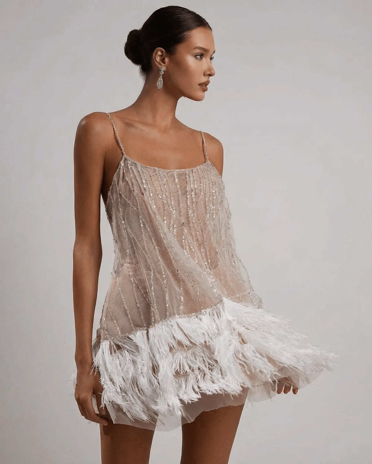 Side profile of the sequin slip dress with feather trim, showing the flared silhouette and sheer overlay