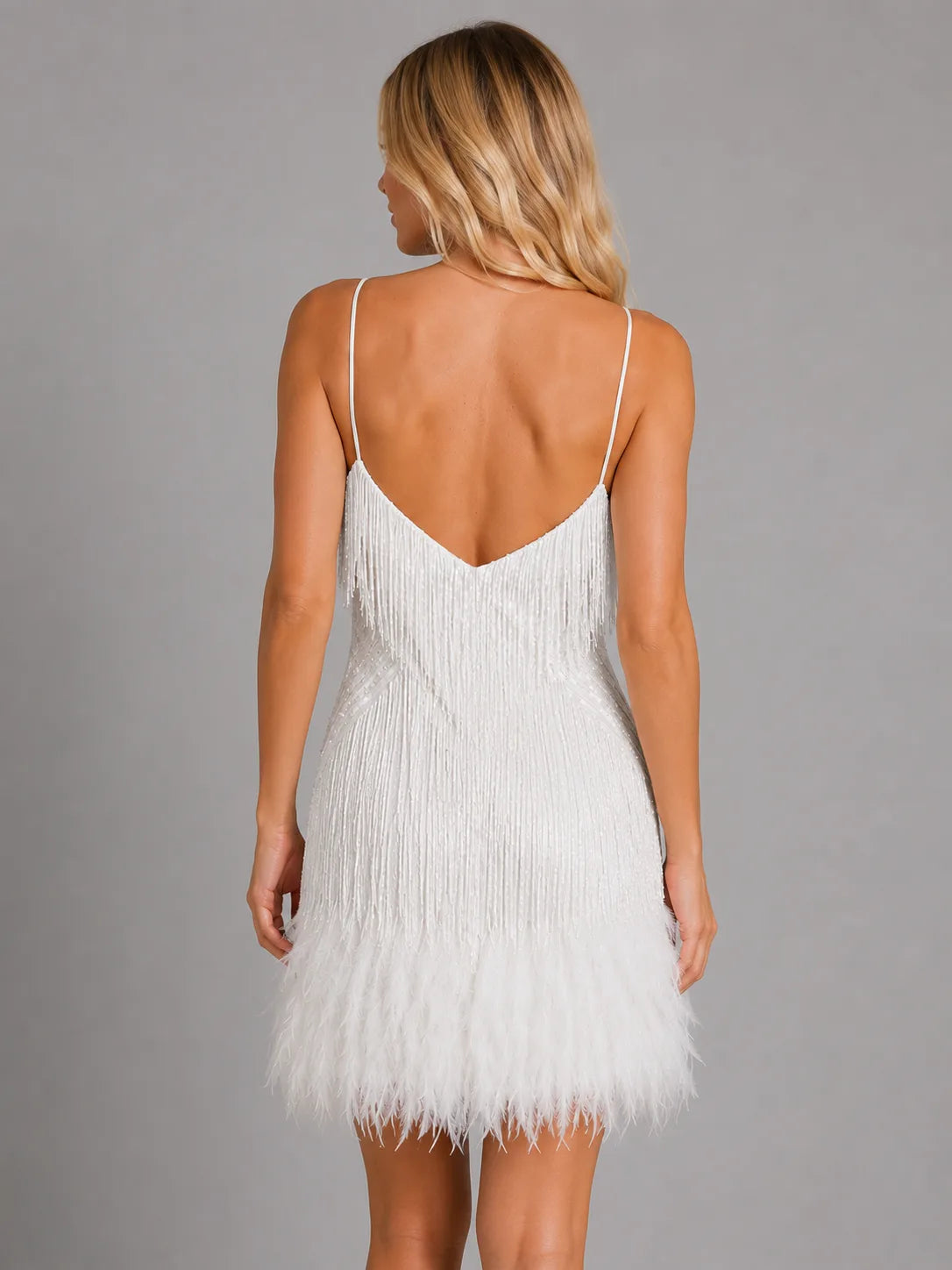 Back view of the white fringe mini dress showing a low back and cascading sequin strands to the feather trim