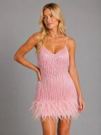 Pink sequin fringe mini dress with feather hem, styled with one hand on the hip