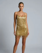 Full-length front view of a woman wearing the gold metallic fringe mini dress with a scoop neckline