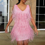 Pink sequin fringe mini dress with V-neck straps, photographed outdoors against a stone building facade