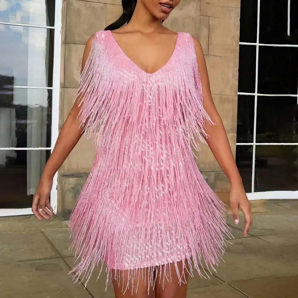 Pink sequin fringe mini dress with V-neck straps, photographed outdoors against a stone building facade