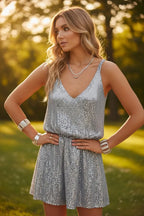 Woman in a silver sequin mini dress with V-neck and thin straps posing outdoors in golden sunlight