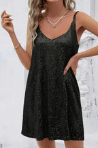 Front view of a black sequin mini dress with V-neckline styled with layered gold necklaces