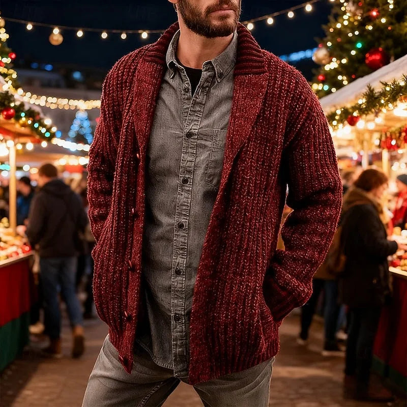 Man in a deep red chunky knit shawl collar cardigan with toggle-style buttons, walking through a festive evening market