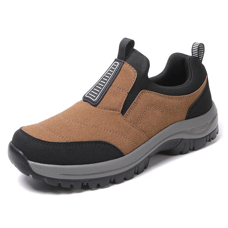 Close-up front angle of khaki slip-on trainer with black pull tab and textured grey outsole on light background