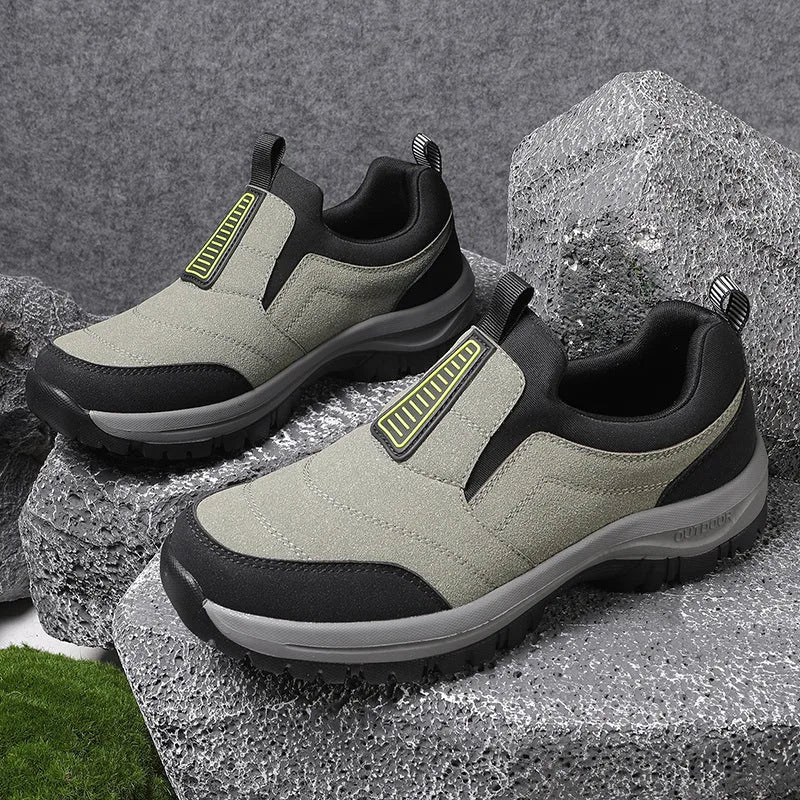 Close-up of black slip-on trainer worn on foot mid-step, highlighting the grey lugged outsole and ankle pull loop
