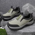 Close-up of black slip-on trainer worn on foot mid-step, highlighting the grey lugged outsole and ankle pull loop