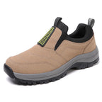 Light grey slip-on trainer with black panels, front angled view showing elastic side gores on rocky stone surface