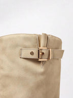 Close-up of the gold buckle hardware and stitched leather strap detail on a beige knee-high boot shaft