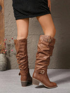 Back view of tan slouched boots walking, highlighting the ruched shaft and ankle buckle strap