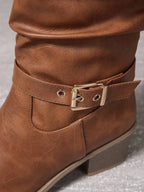 Close-up of the gold buckle and grommet detail on the ankle strap of a tan knee-high boot