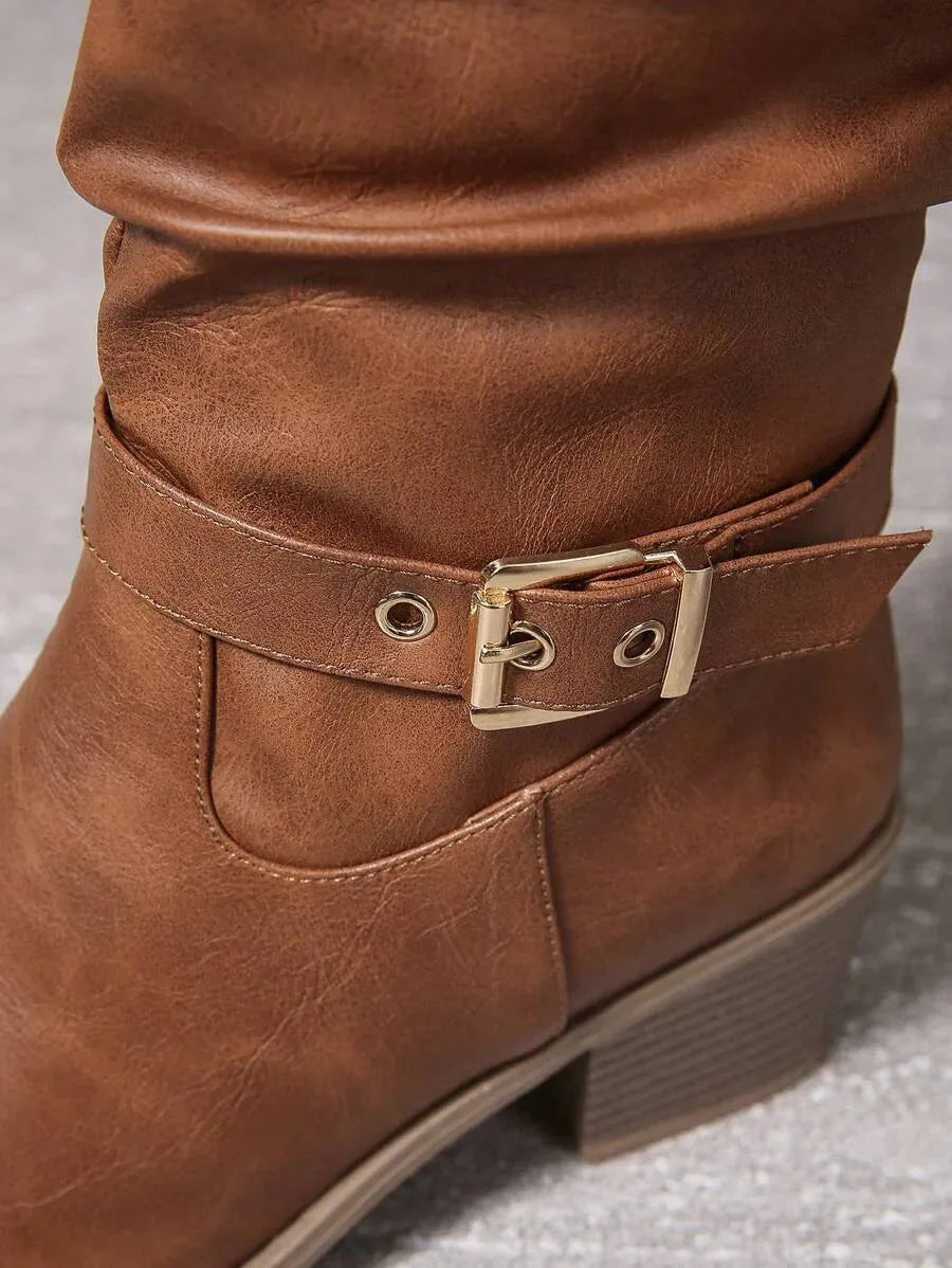 Close-up of the gold buckle and grommet detail on the ankle strap of a tan knee-high boot
