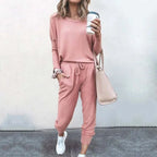 Woman in a pink loungewear set with drawstring joggers and oversized top, holding a coffee cup and pink tote bag